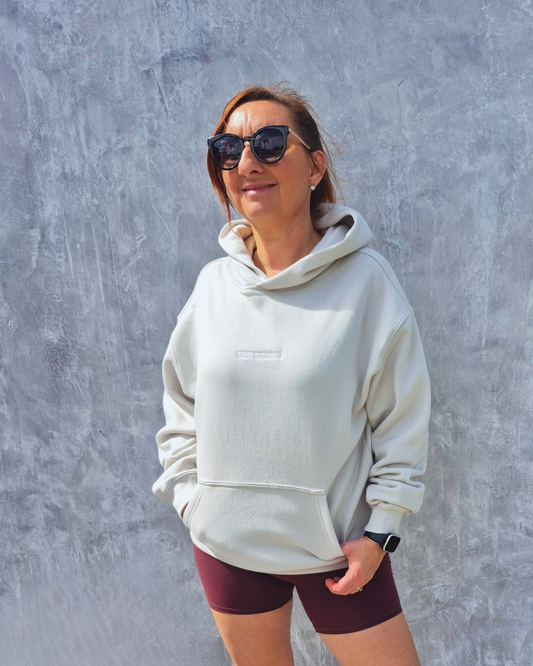 STRYD Performance Elite Unisex Hoodie in Bone — front view on female model, relaxed boxy silhouette, self-fabric lined hood | Premium gym wear Australia
