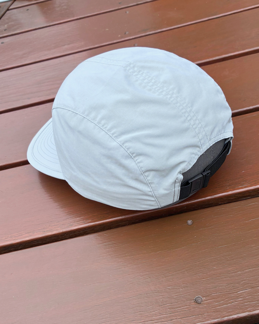 Light weight nylon sweat wicking running cap in stone grey colour with STRYD Performance logo on front, performance premium running cap Left side view showing adjustable fit band