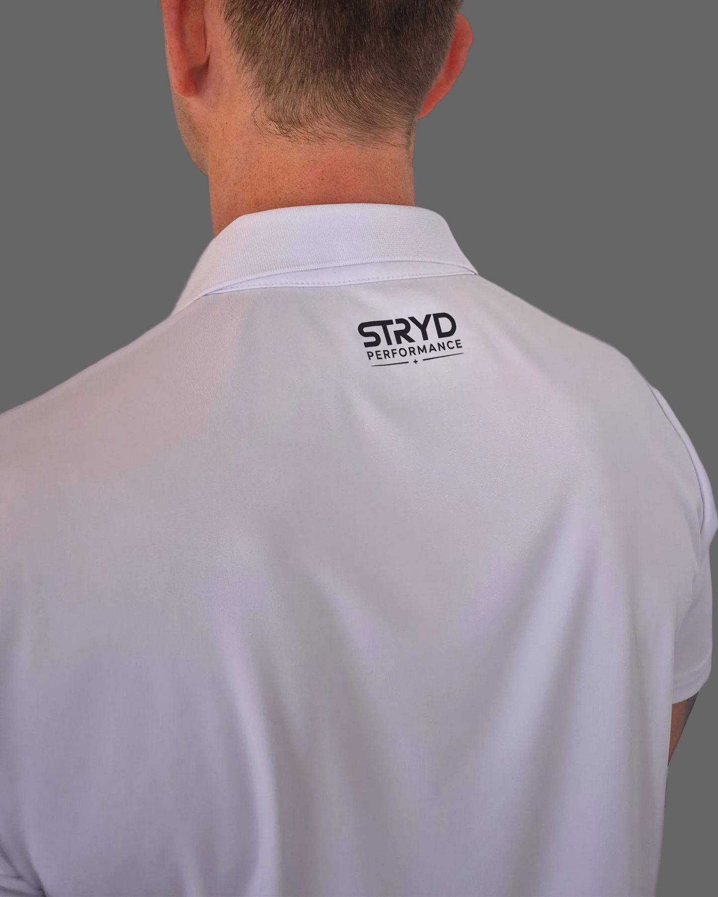 White shirt with 'STRYD PERFORMANCE' logo on the back, worn by a person against a light purple background.