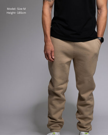 STRYD Performance Elite Unisex Track Pant in Sand — front view on male model, relaxed regular fit, elasticated waistband | Premium 320GSM fleece activewear Australia, Sunshine Coast 
activewear and gym wear Queensland, fast shipping within 24hrs of order and free shipping when you spend $150 AUD, Tracksuit pants, athleisure winter sets, premium apparel
