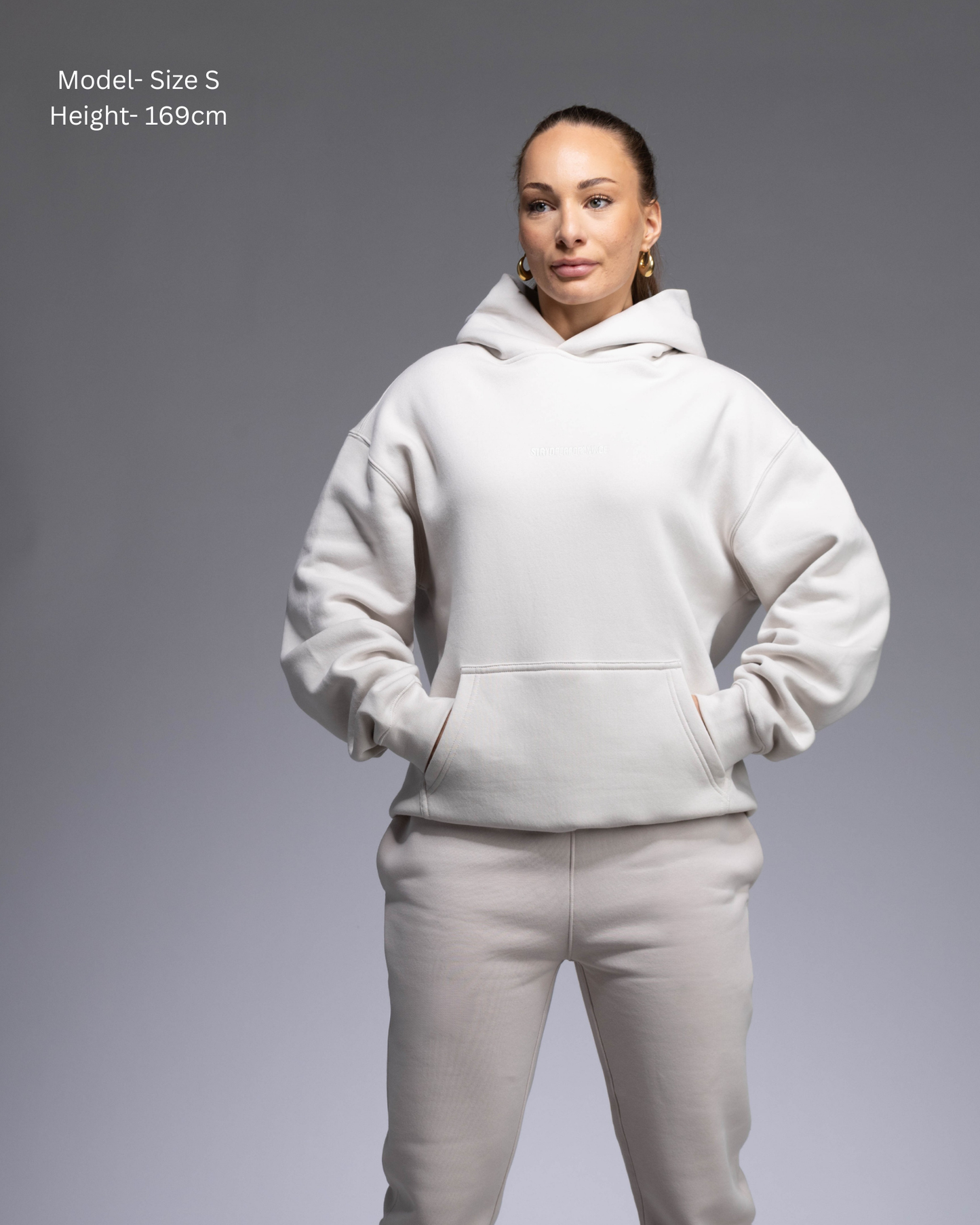 STRYD Performance Elite Unisex Hoodie in Bone — female  model showing the unisex fit, relaxed boxy silhouette, self-fabric lined hood | Premium gym wear Australia front view
