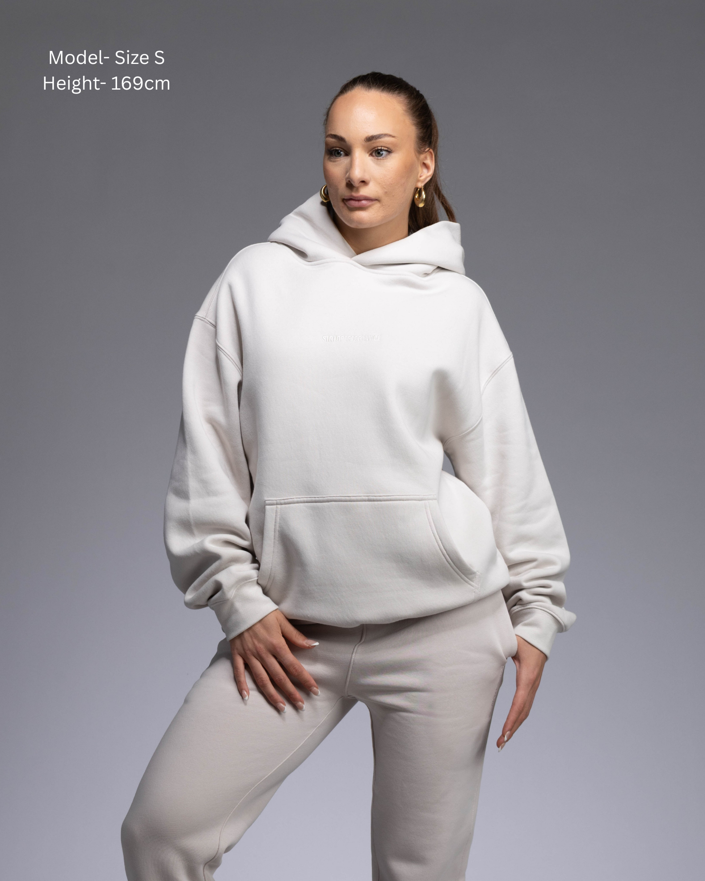 STRYD Performance Elite Unisex Hoodie in Bone — female  model showing the unisex fit, relaxed boxy silhouette, self-fabric lined hood | Premium gym wear Australia front view

