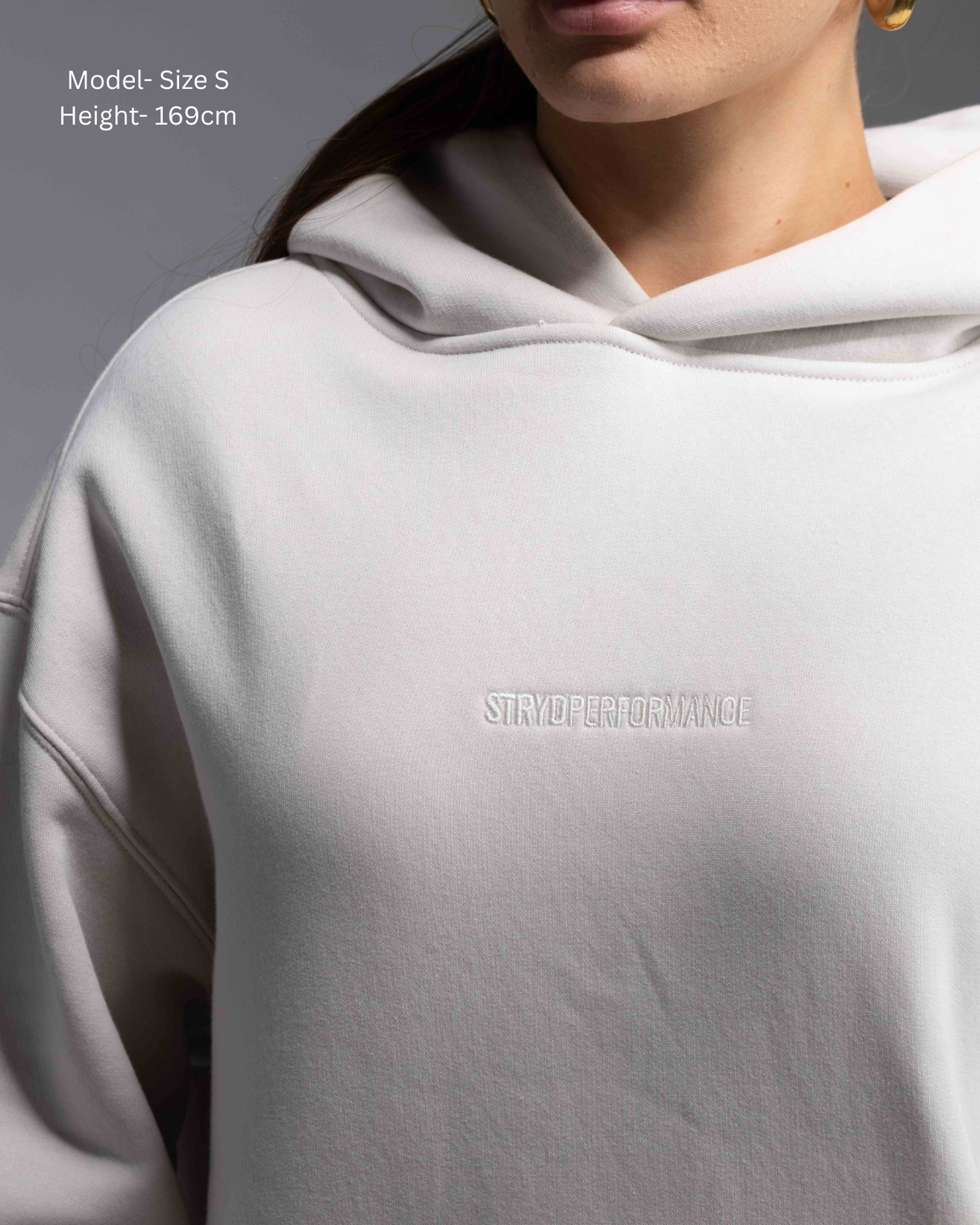 STRYD Performance Elite Unisex Hoodie in Bone — female  model showing the unisex fit, relaxed boxy silhouette, self-fabric lined hood | Premium gym wear Australia front detailed view
