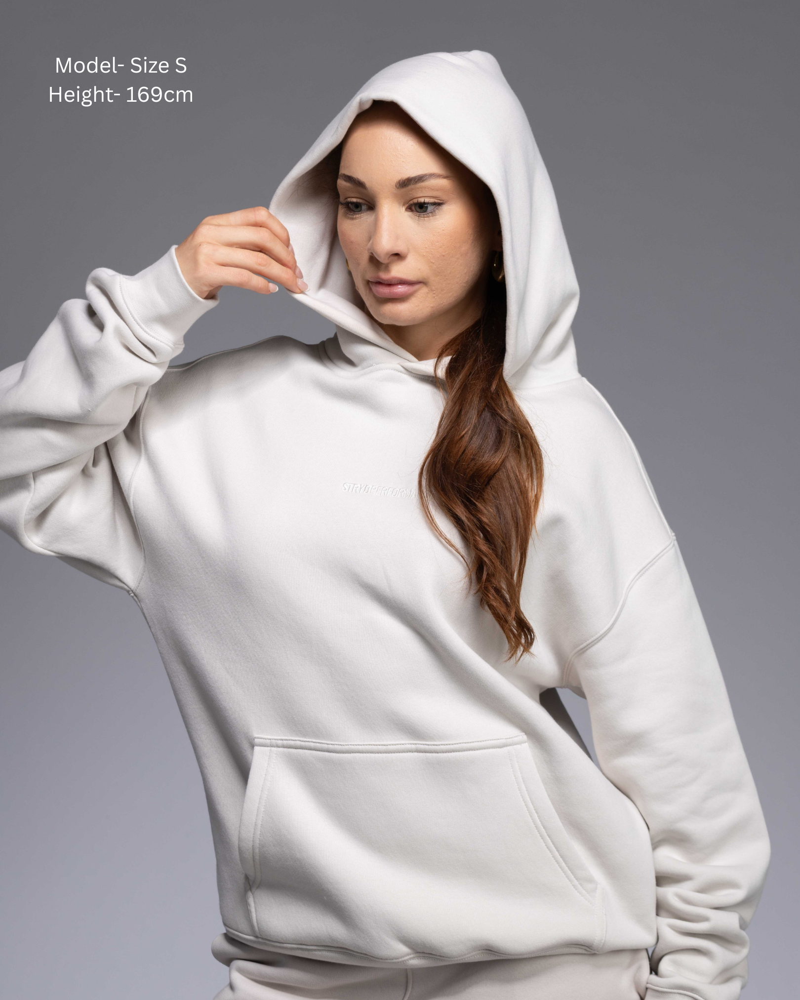 STRYD Performance Elite Unisex Hoodie in Bone — female  model showing the unisex fit, relaxed boxy silhouette, self-fabric lined hood | Premium gym wear Australia front view with hoodie on lifestyle shot
