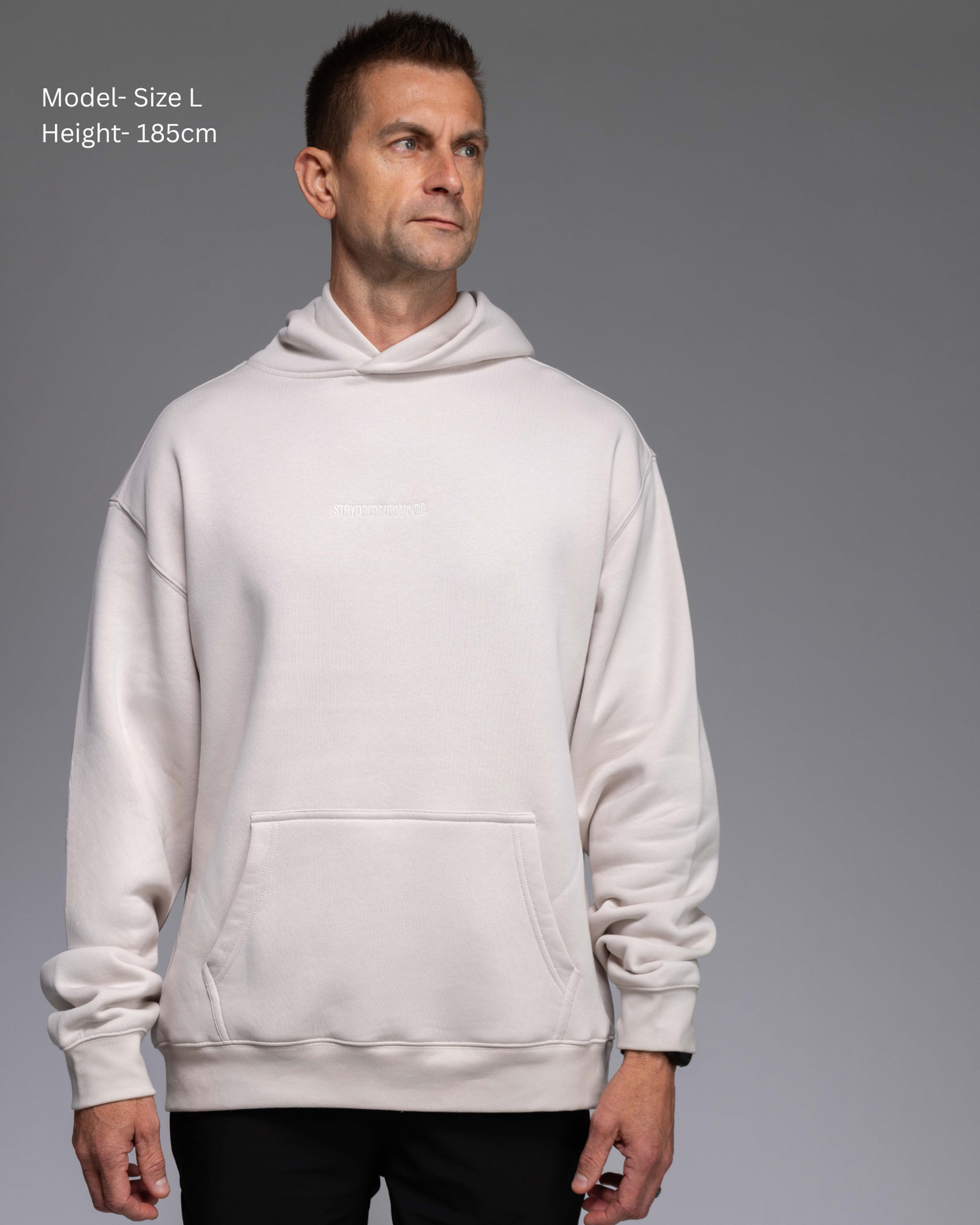 STRYD Performance Elite Unisex Hoodie in Bone — male  model showing the unisex fit, relaxed boxy silhouette, self-fabric lined hood | Premium gym wear Australia front view
