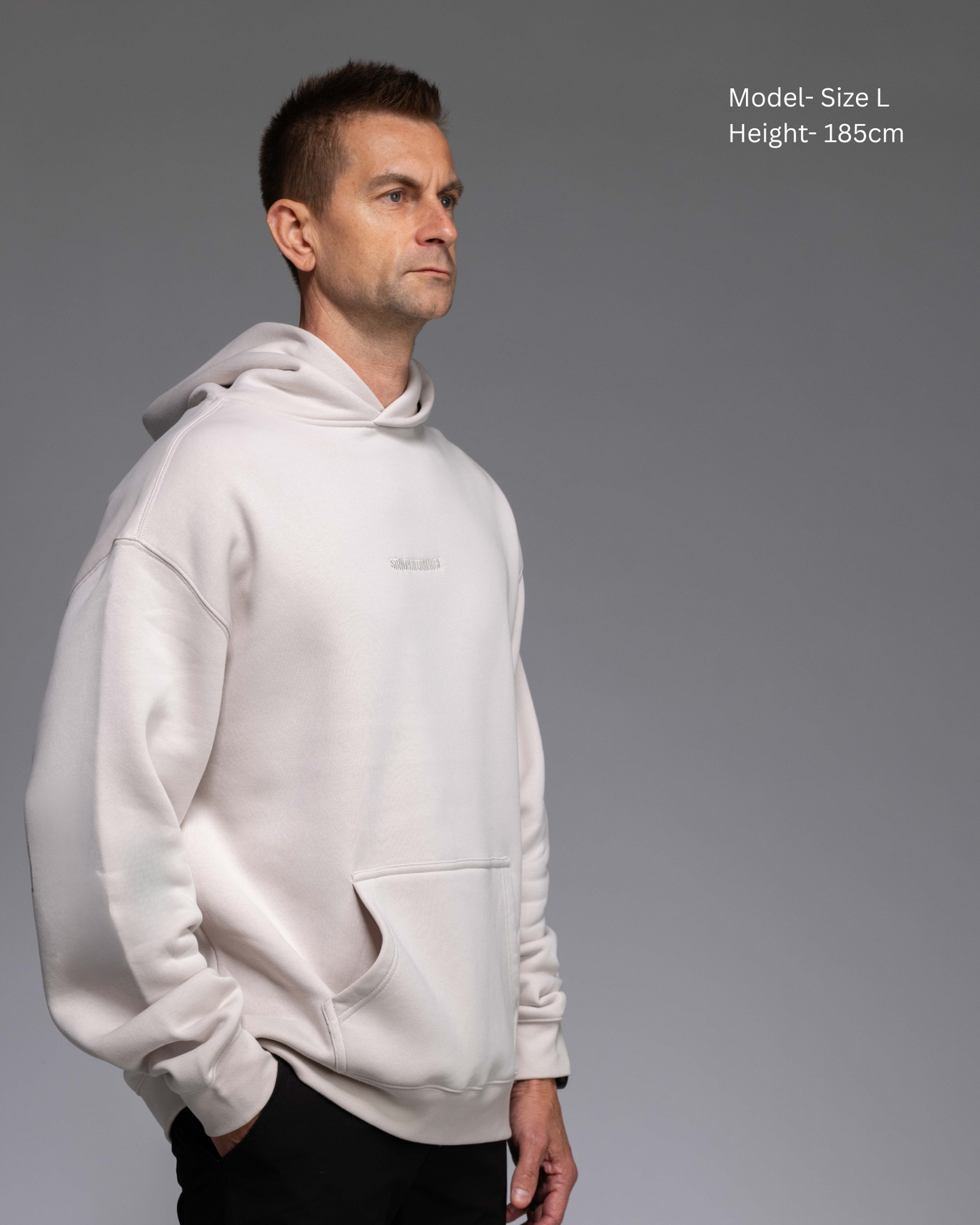 STRYD Performance Elite Unisex Hoodie in Bone — male  model showing the unisex fit, relaxed boxy silhouette, self-fabric lined hood | Premium gym wear Australia front view
