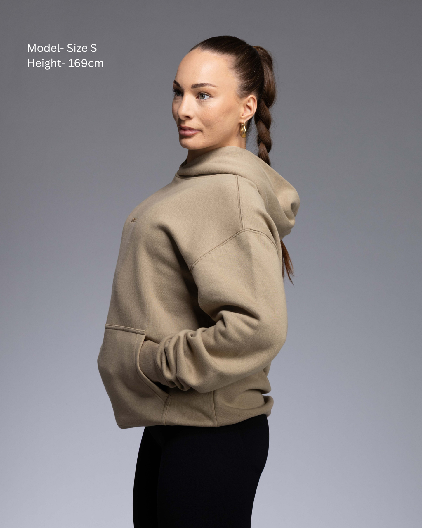 Premium Drop shoulder STRYD Performance Elite Unisex Hoodie in Sand — 320 GSM fleece, relaxed fit, drop-shoulder, ribbed cuffs, premium activewear Australia, Sunshine Coast activewear shop now free shipping over $150 side View of Elite Hood Female Model