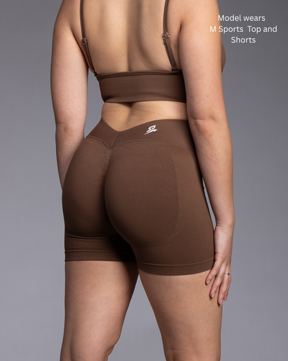 Person wearing a brown sports top and shorts on a gray background