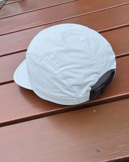 Light weight nylon sweat wicking running cap in stone grey colour with STRYD Performance logo on front, performance premium running cap Left side view showing adjustable fit band