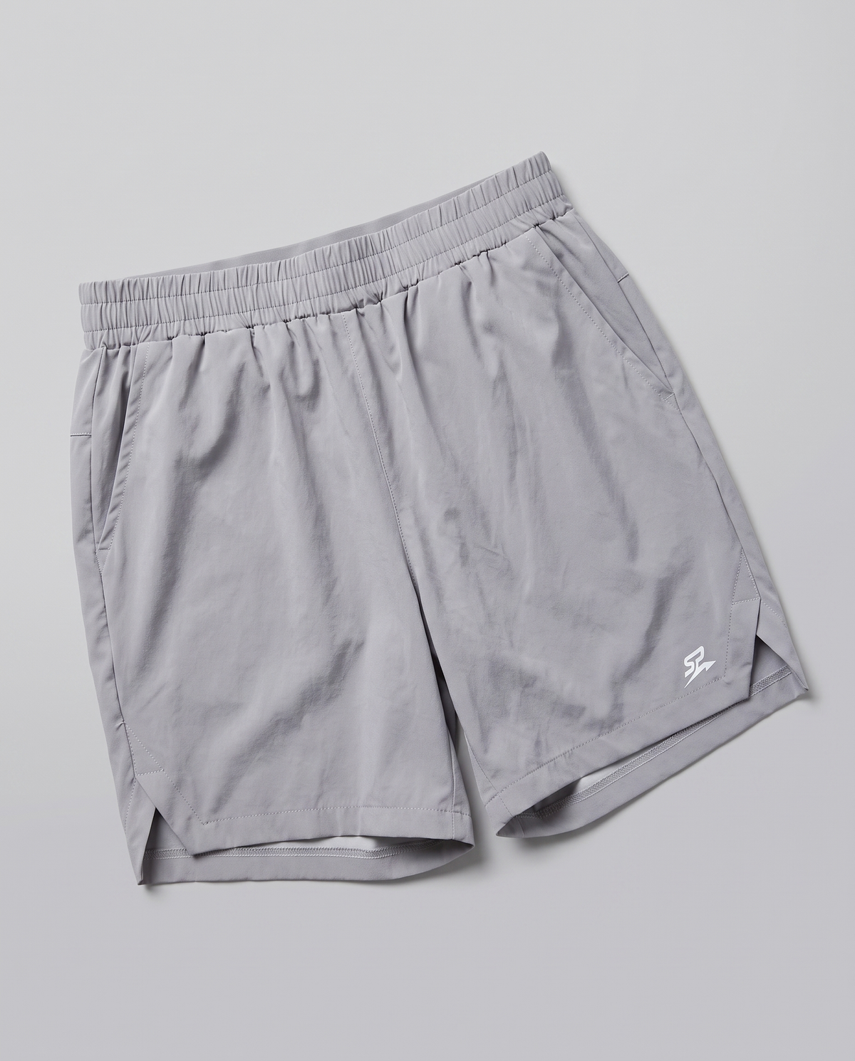 Light gray Apex athletic shorts with an elastic waistband and a small white stylized logo on the lower left hem, shown on a neutral gray background.