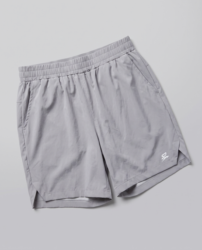 Light gray Apex athletic shorts with an elastic waistband and a small white stylized logo on the lower left hem, shown on a neutral gray background.
