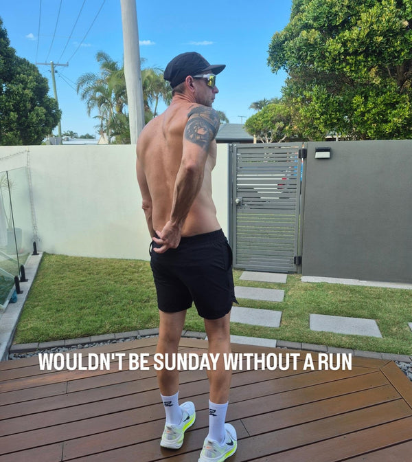 Man after a Sunday run in black APEX training shorts, run cap and crew socks
